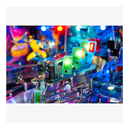 Close-up of a pinball machine with colorful lights and mechanical components, set against a blurred amusement park background.
