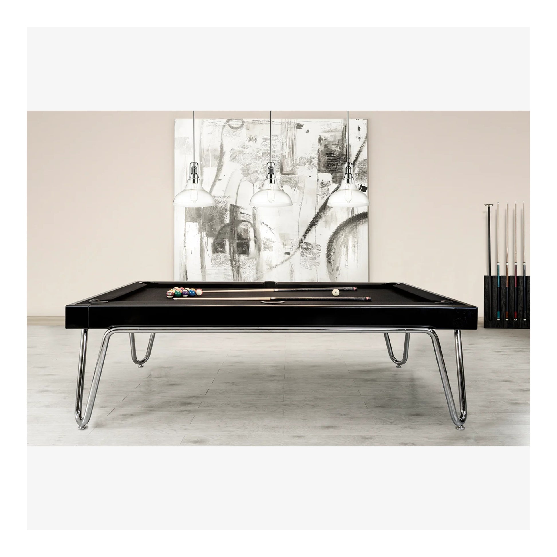 Black pool table with chrome legs in a room with abstract art on the wall.