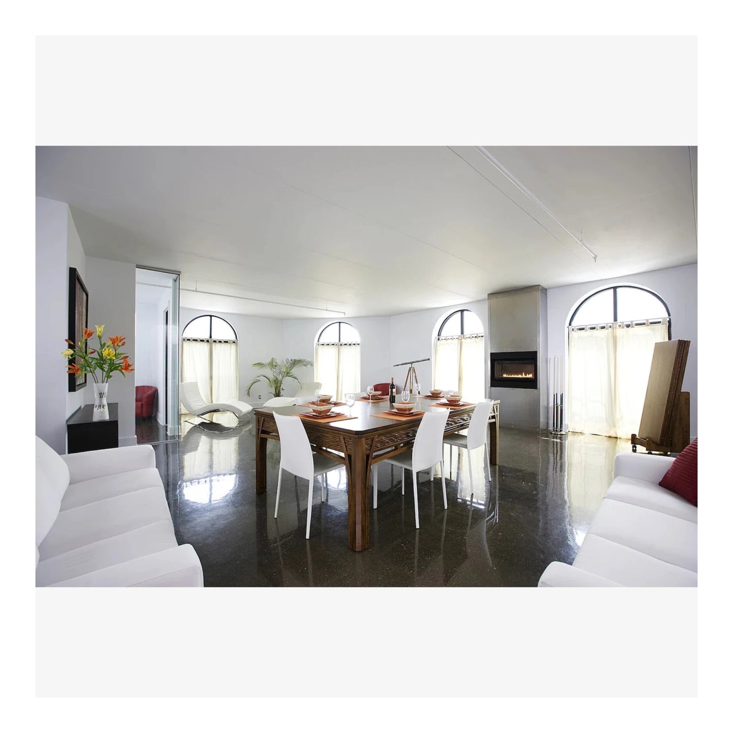 Modern living room with a dining table and chairs, white walls, and a fireplace.