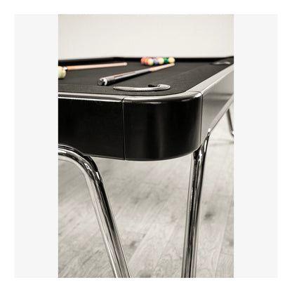 Black pool table with cues on a light wood floor