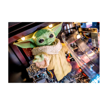 Green alien-like creature with large eyes and a yellow outfit in a blurred indoor setting