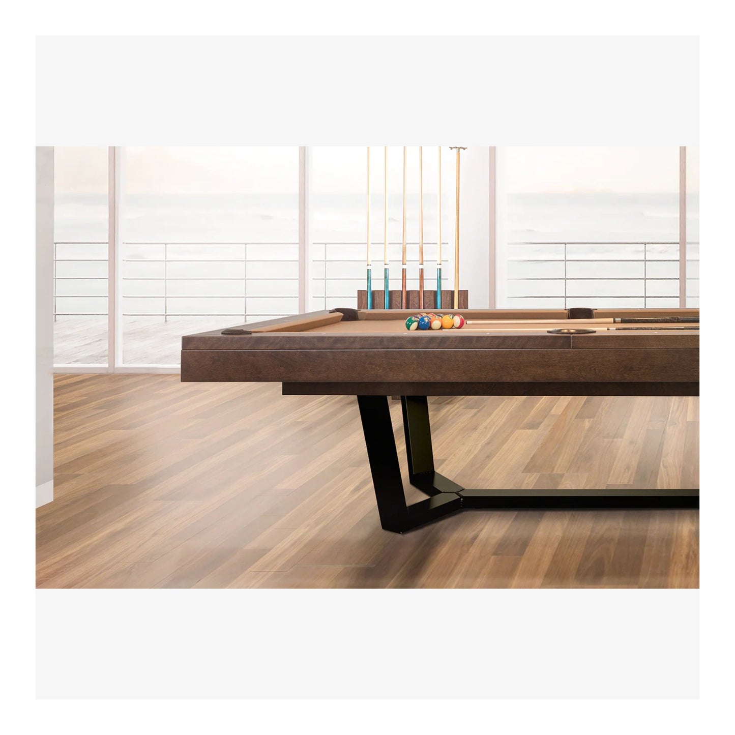 Wooden pool table with pool cues and balls on a wooden floor.