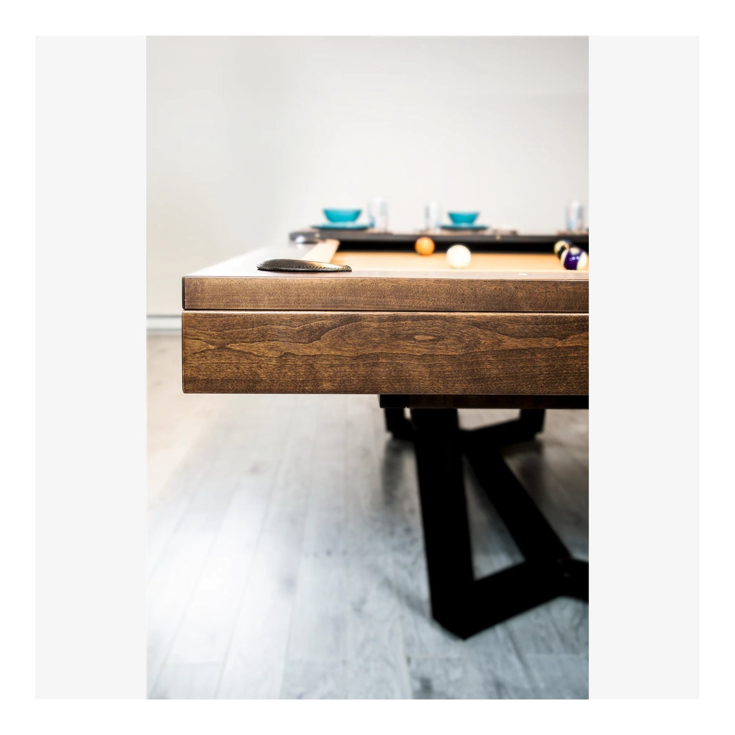 Wooden pool table with pool balls on a light gray floor