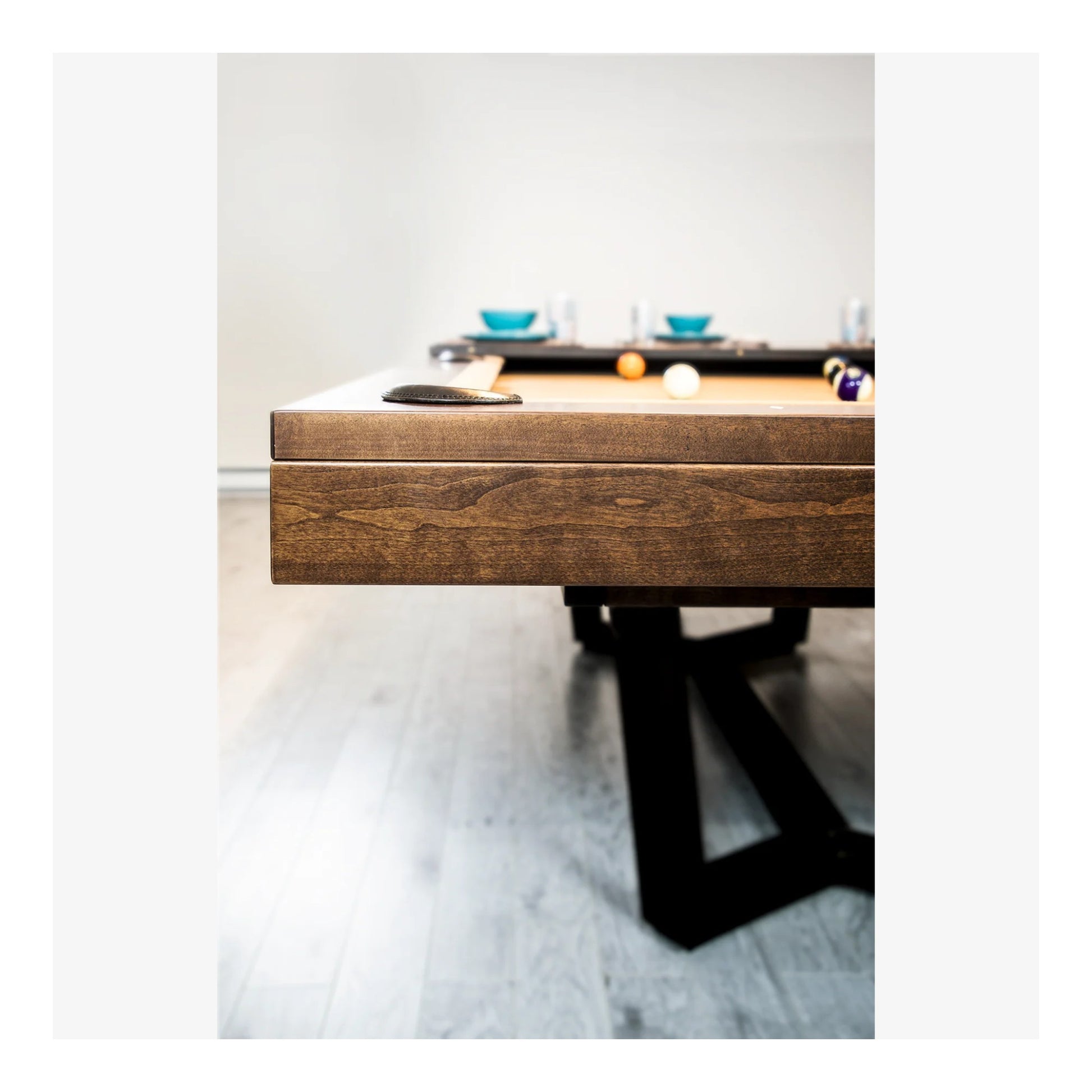 Wooden pool table with pool balls on a light gray floor