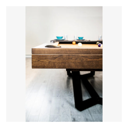 Wooden pool table with pool balls on a light gray floor