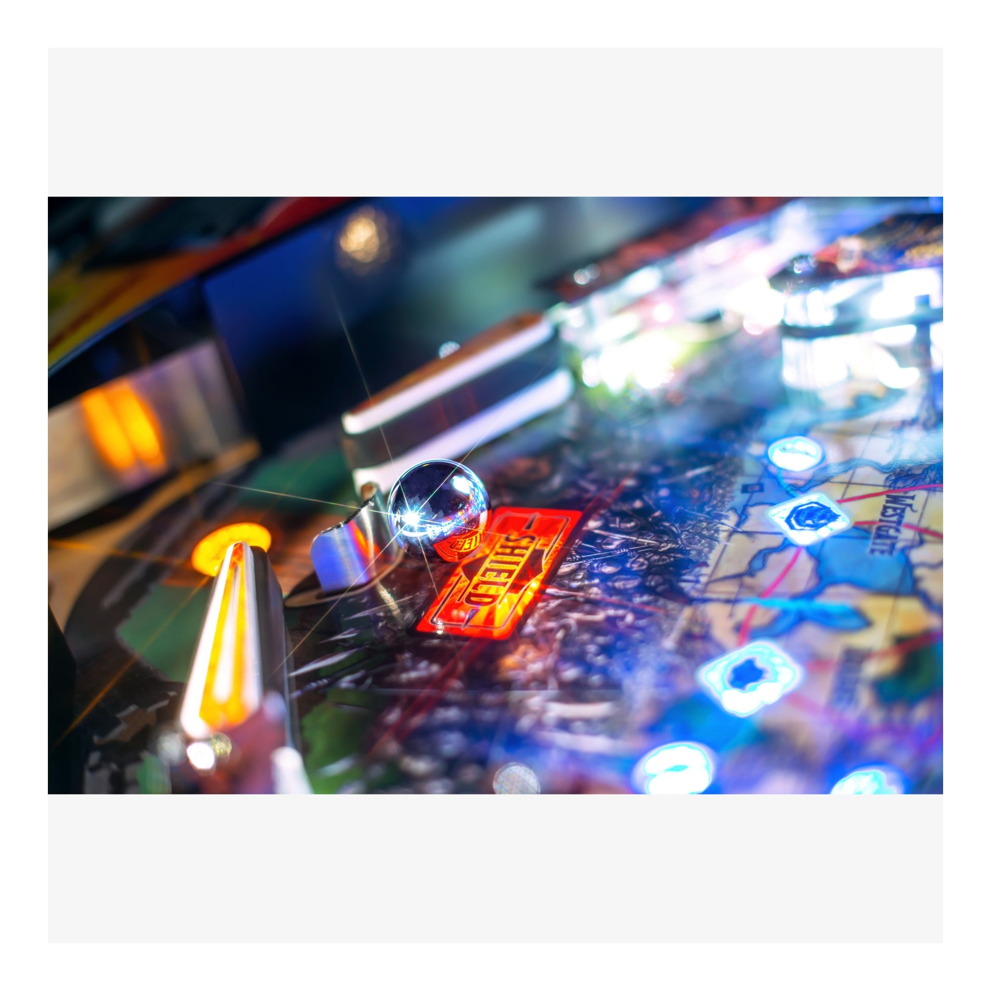 Close-up of a pinball machine with colorful lights and playing field.