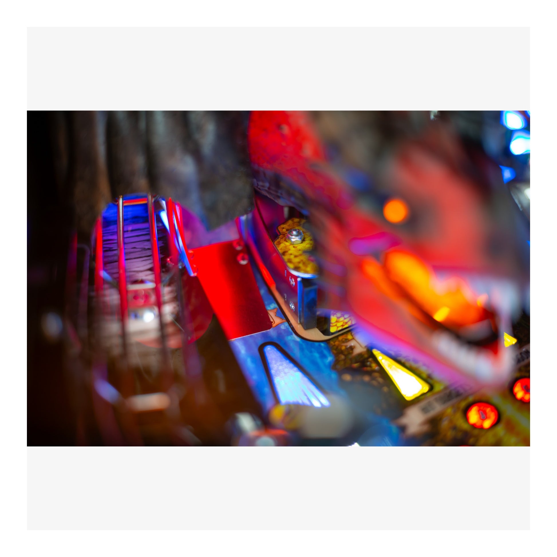 Close-up of a colorful pinball machine with bright lights and reflections.