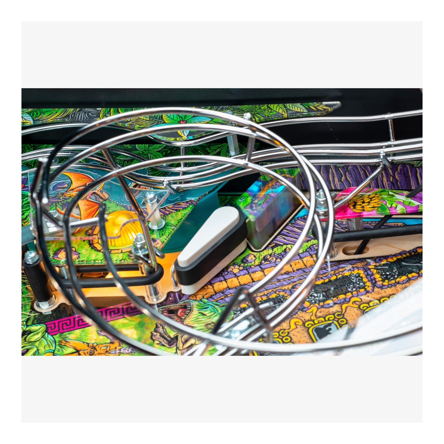 Close-up of a pinball machine with colorful artwork and a large metal hoop.