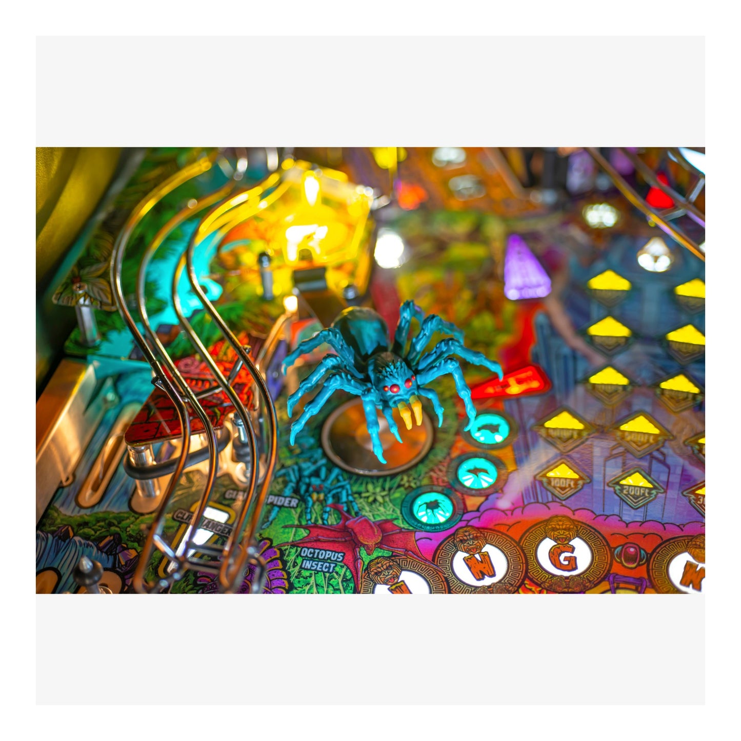 Colorful pinball machine with a blue spider figure and various lights.