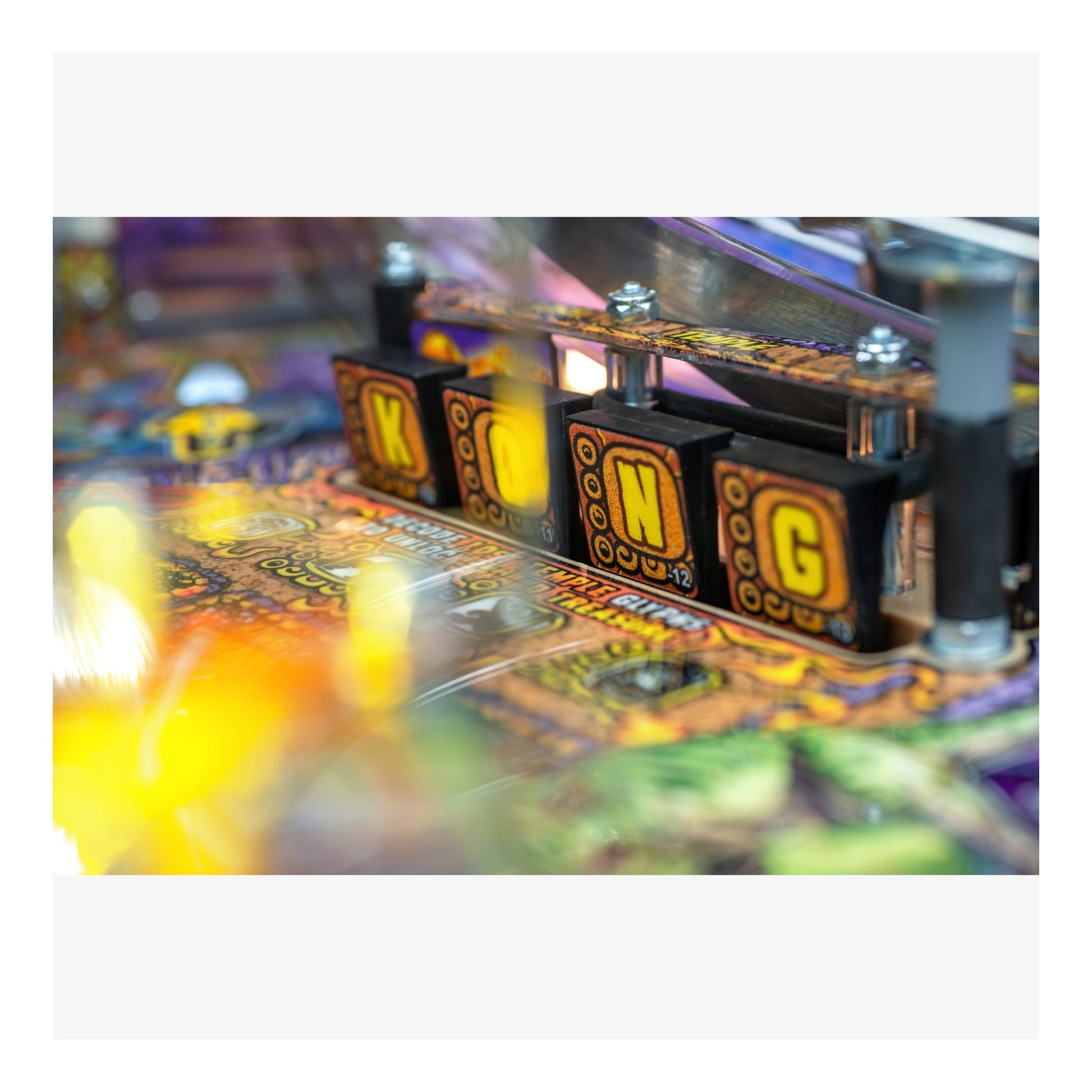 Close-up of a pinball machine with colorful playfield and mechanical components.