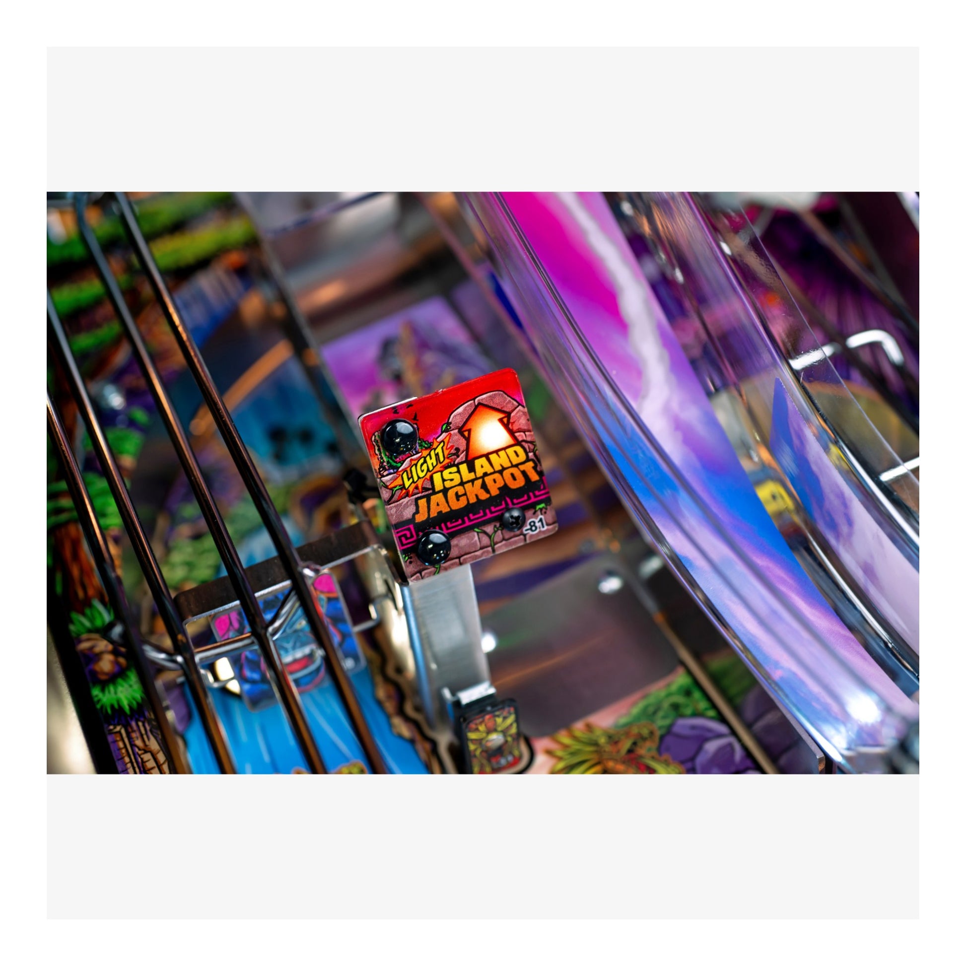 Close-up of a pinball machine with colorful playfield and 'Ghost Island Jackpot' label.