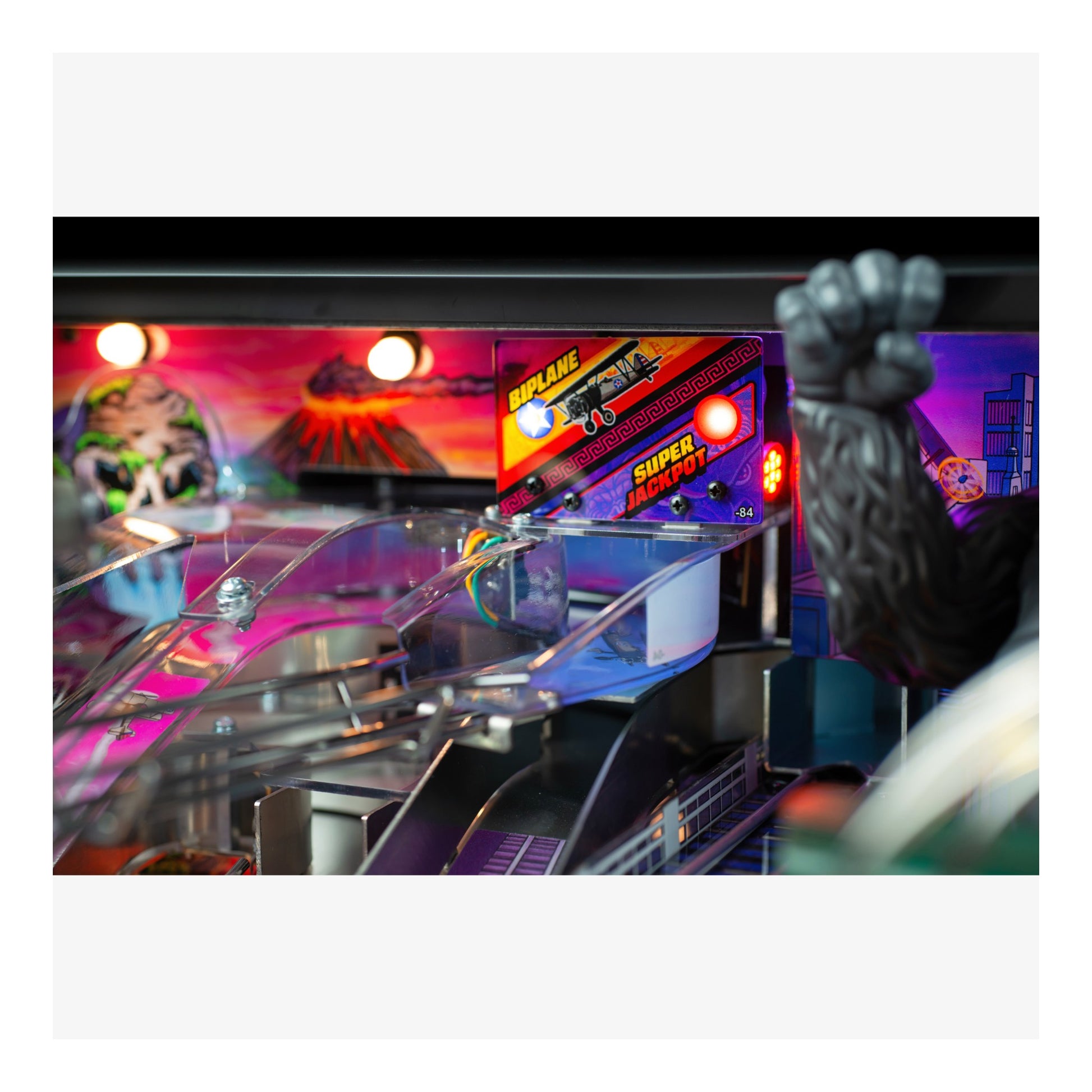 Pinball machine with colorful lights and a person's hand reaching towards it