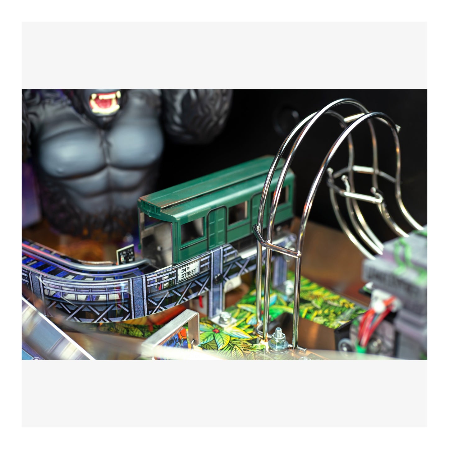 Close-up of a pinball machine with a green train car and metallic track.