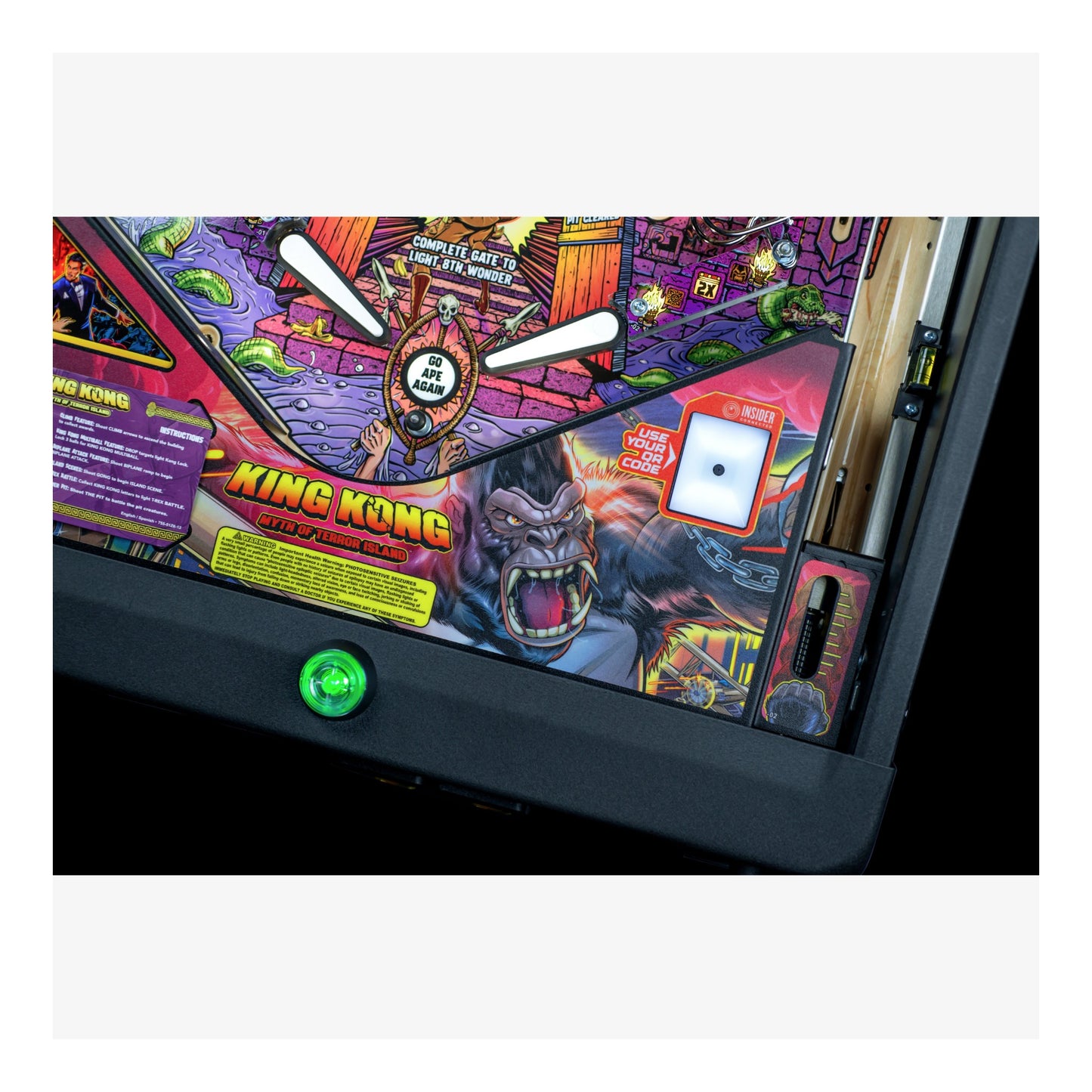 Close-up of a King Kong-themed pinball machine with colorful artwork and a green button.
