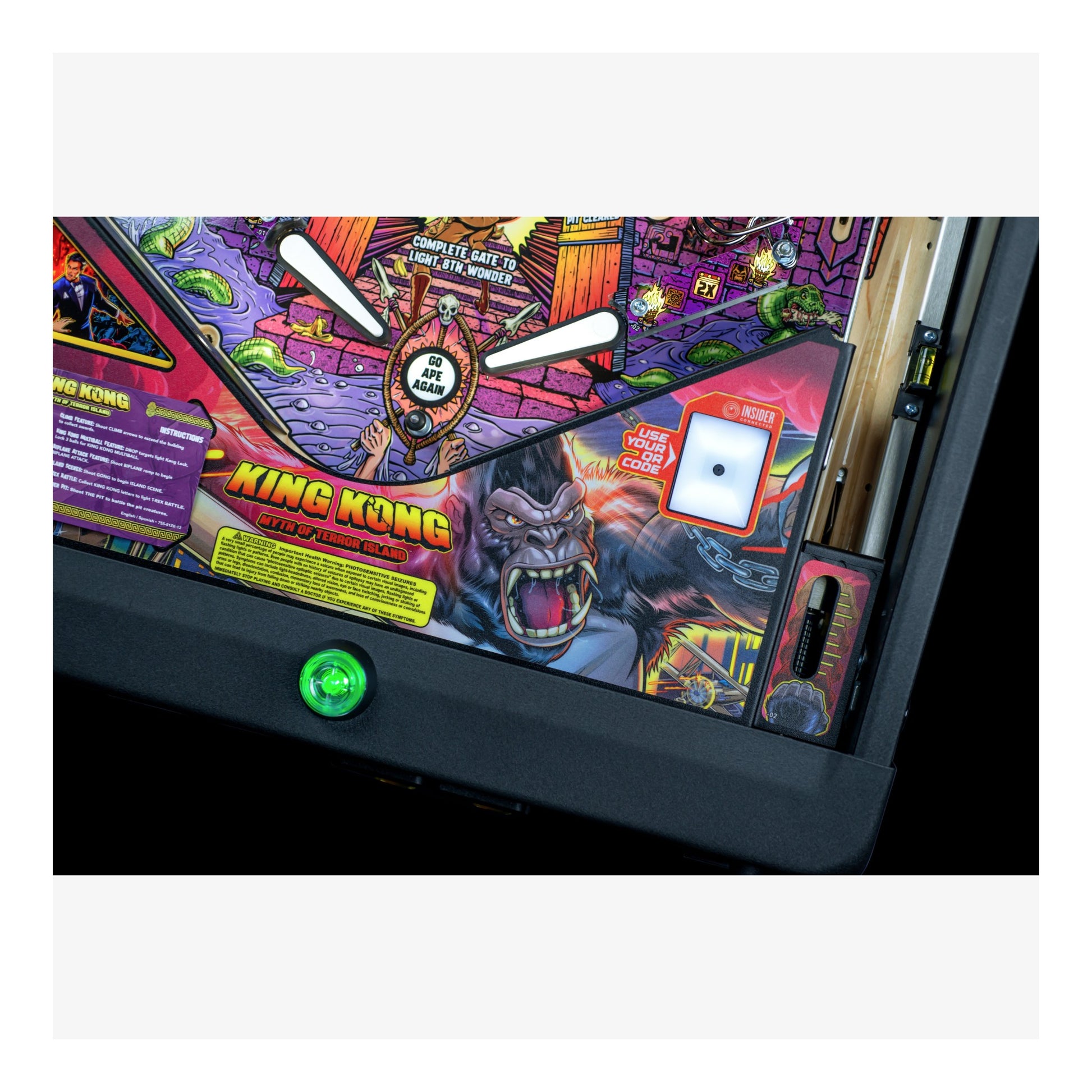 Close-up of a King Kong-themed pinball machine with colorful artwork and a green button.