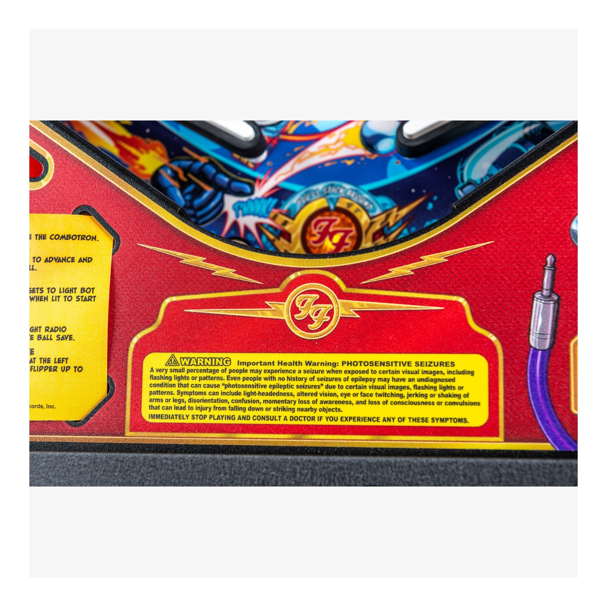 Close-up of a pinball machine with a colorful design and warning label.