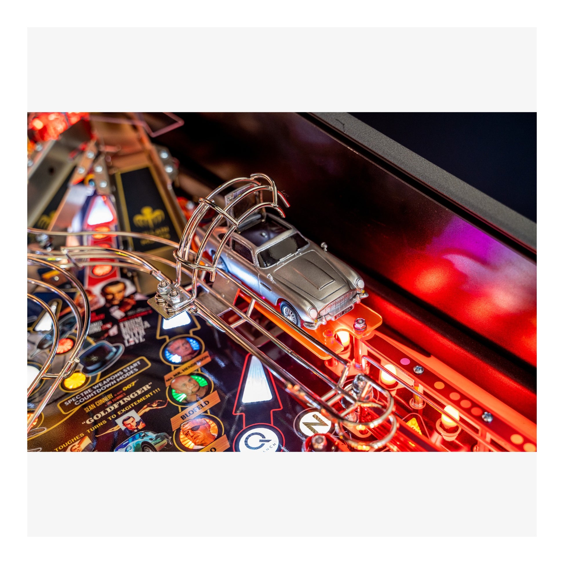Close-up of a pinball machine with a car figure on a colorful playfield.