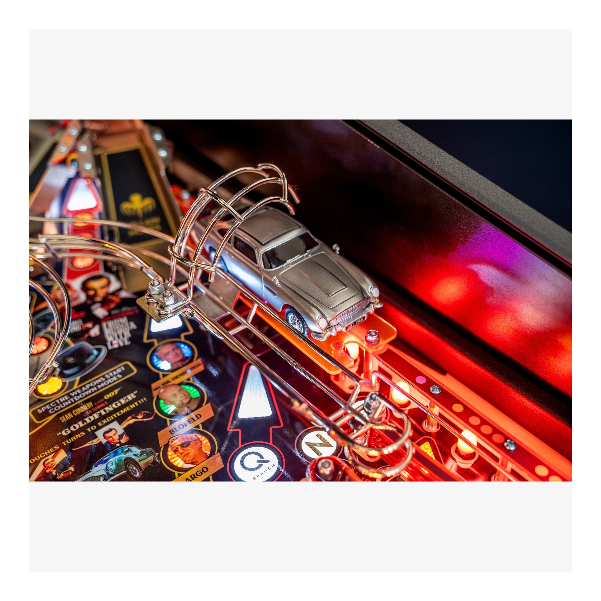 Close-up of a pinball machine with a car figure and colorful playfield.
