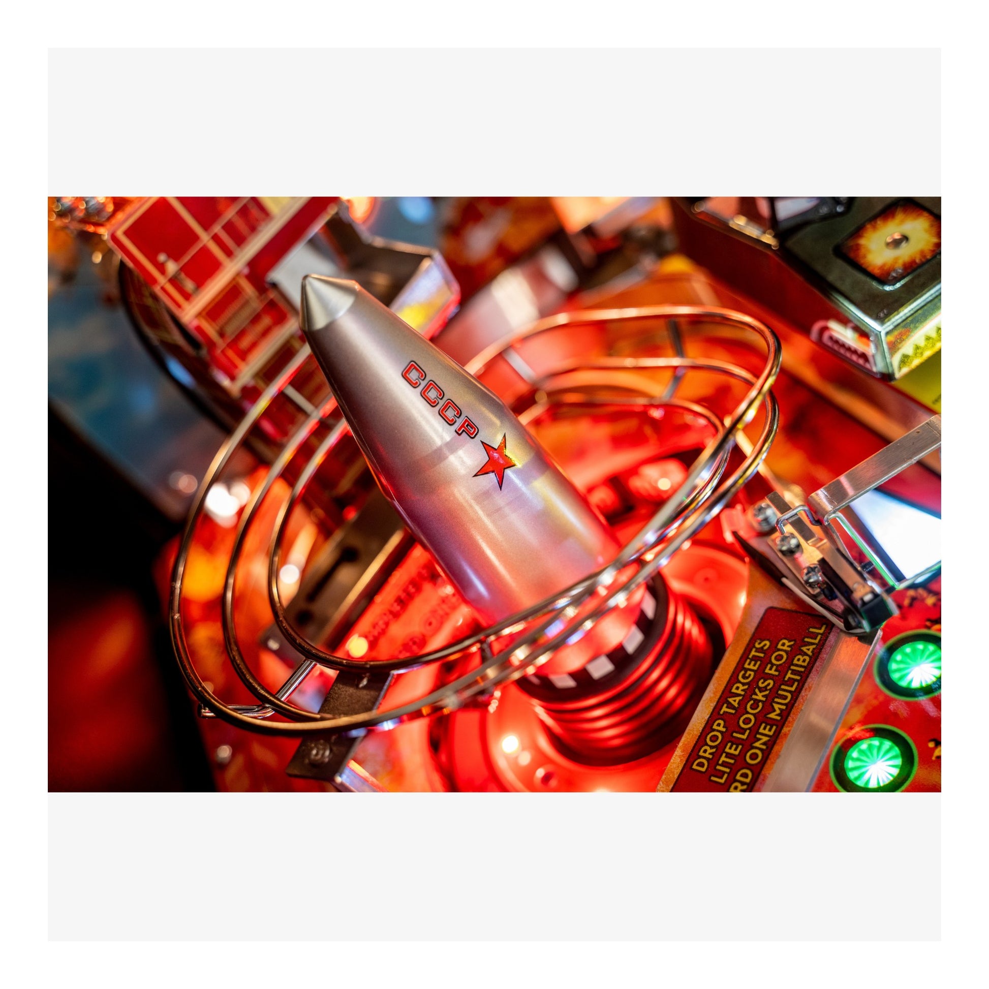 Close-up of a vintage-style pinball machine with a rocket design and 'Coop' branding.