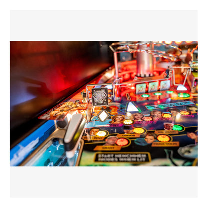 Close-up of a pinball machine with colorful lights and players' faces on the playfield.