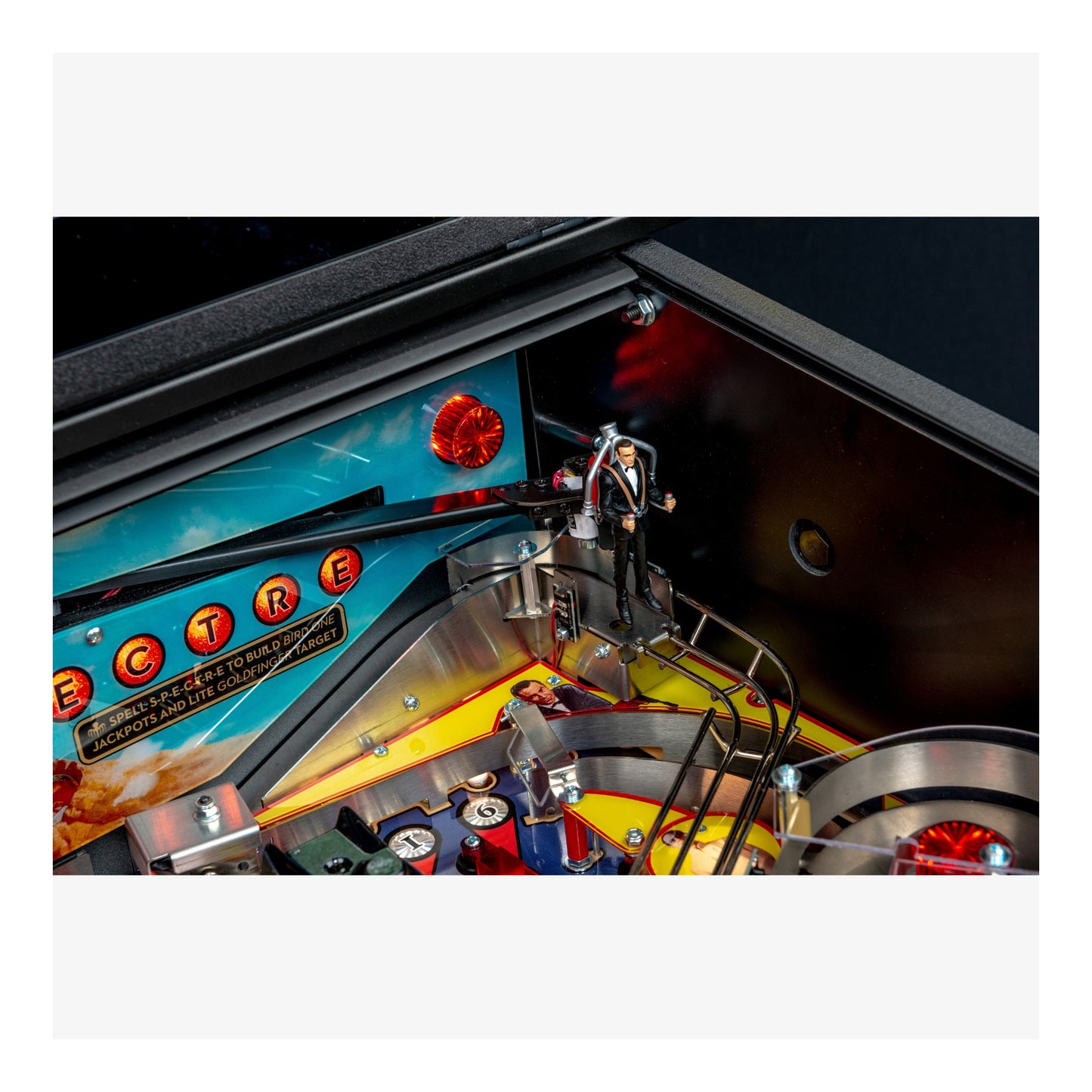 Close-up of a pinball machine with colorful playfield and red lights.