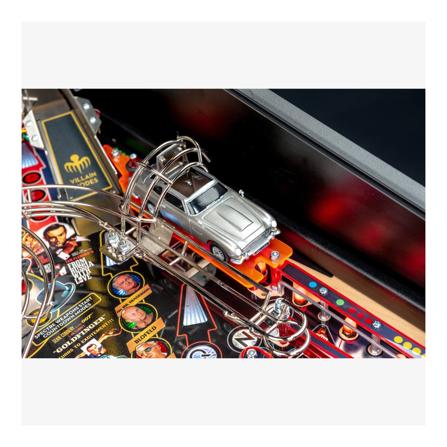 Close-up of a pinball machine with a car figure on a colorful playing field.