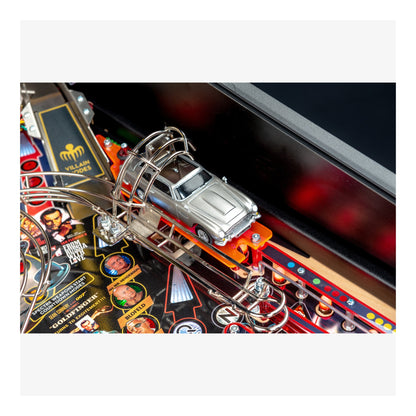 Close-up of a pinball machine with a car figure on a colorful playing field.