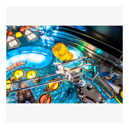 Close-up of a pinball machine with a yellow ball and colorful background