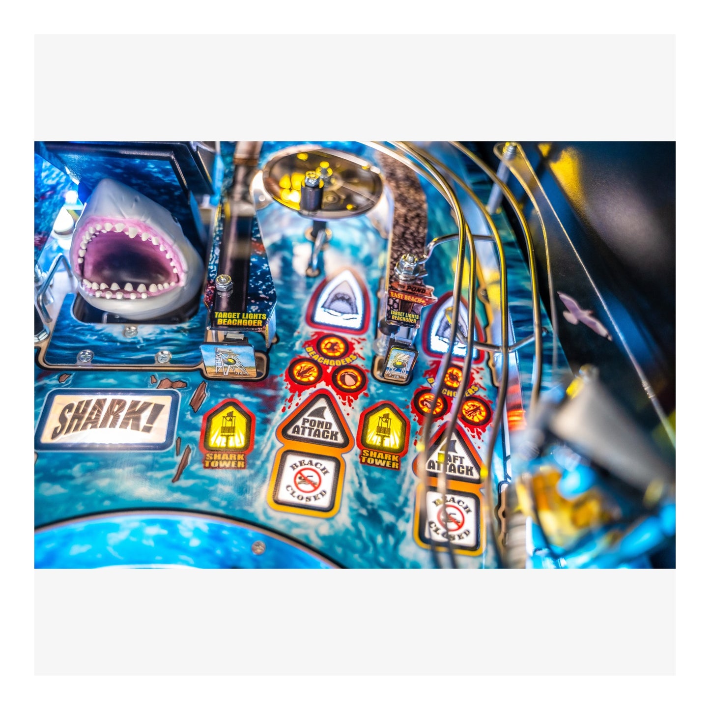 Close-up of a colorful pinball machine with shark-themed artwork and labels.