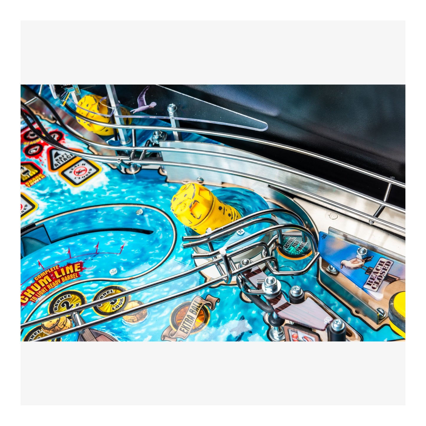 Close-up of a pinball machine with a blue playing field and yellow players.