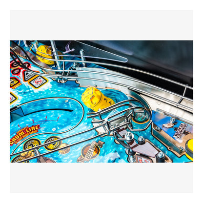 Close-up of a pinball machine with a blue playing field and yellow players.