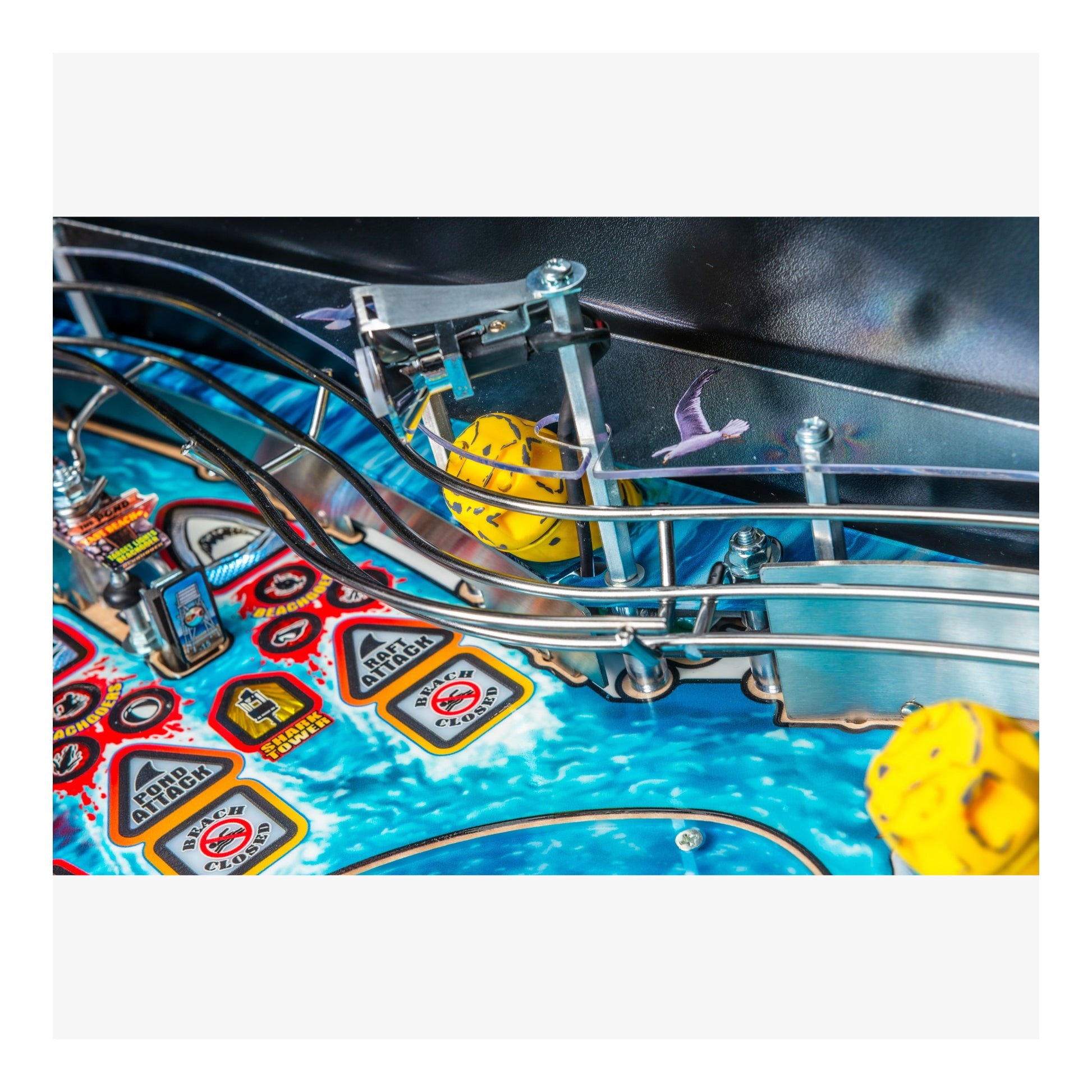Close-up of a pinball machine with colorful playfield and yellow flippers.