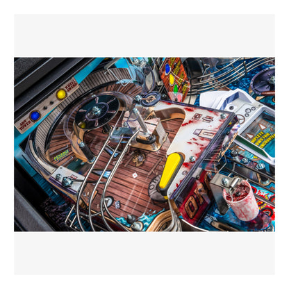 Close-up of a pinball machine with various components and a colorful background.