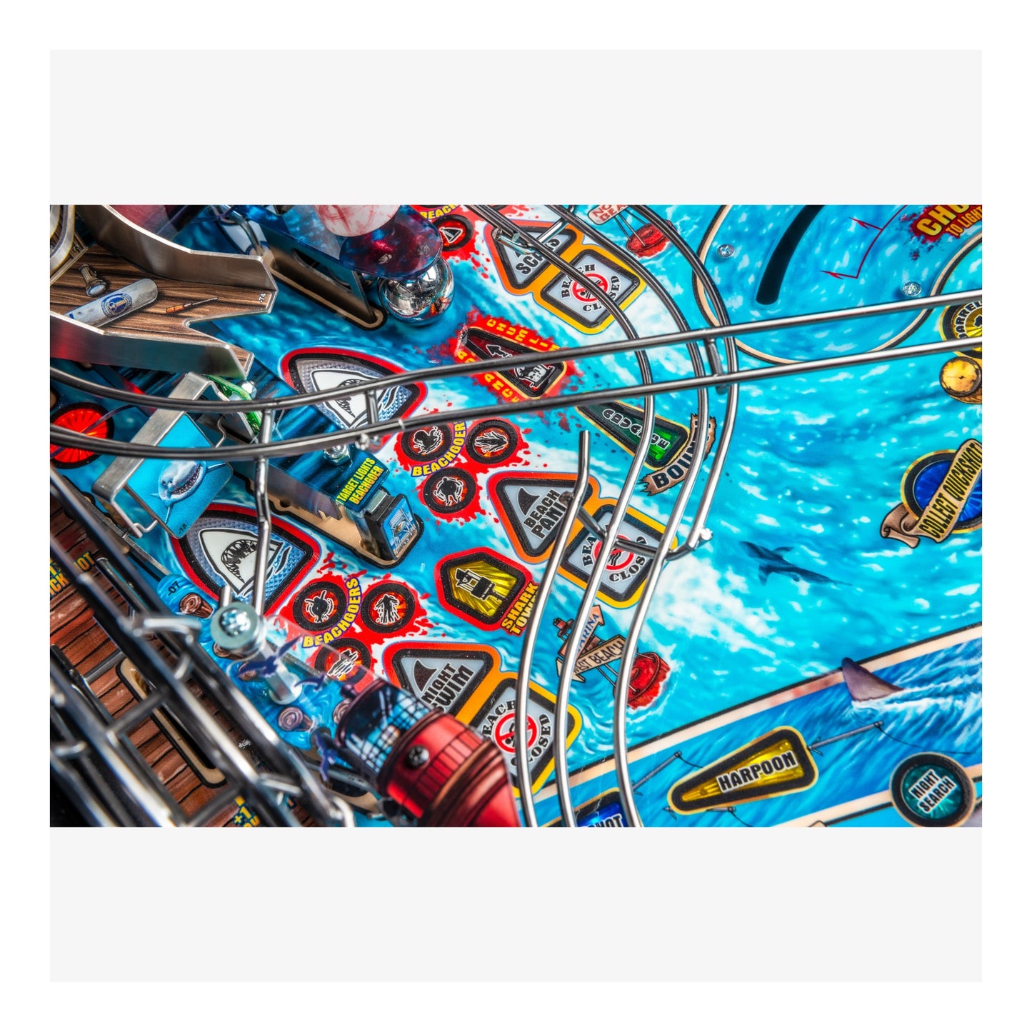 Close-up of a pinball machine playing field with colorful designs and symbols.