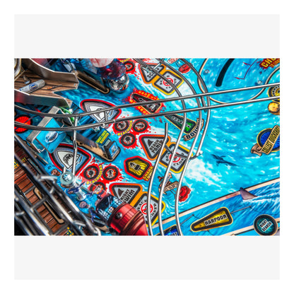 Close-up of a pinball machine playing field with colorful designs and symbols.