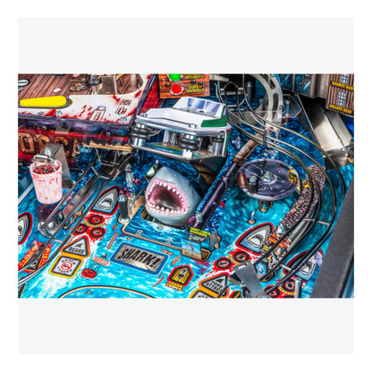 Close-up of a pinball machine with a shark design and colorful playfield.