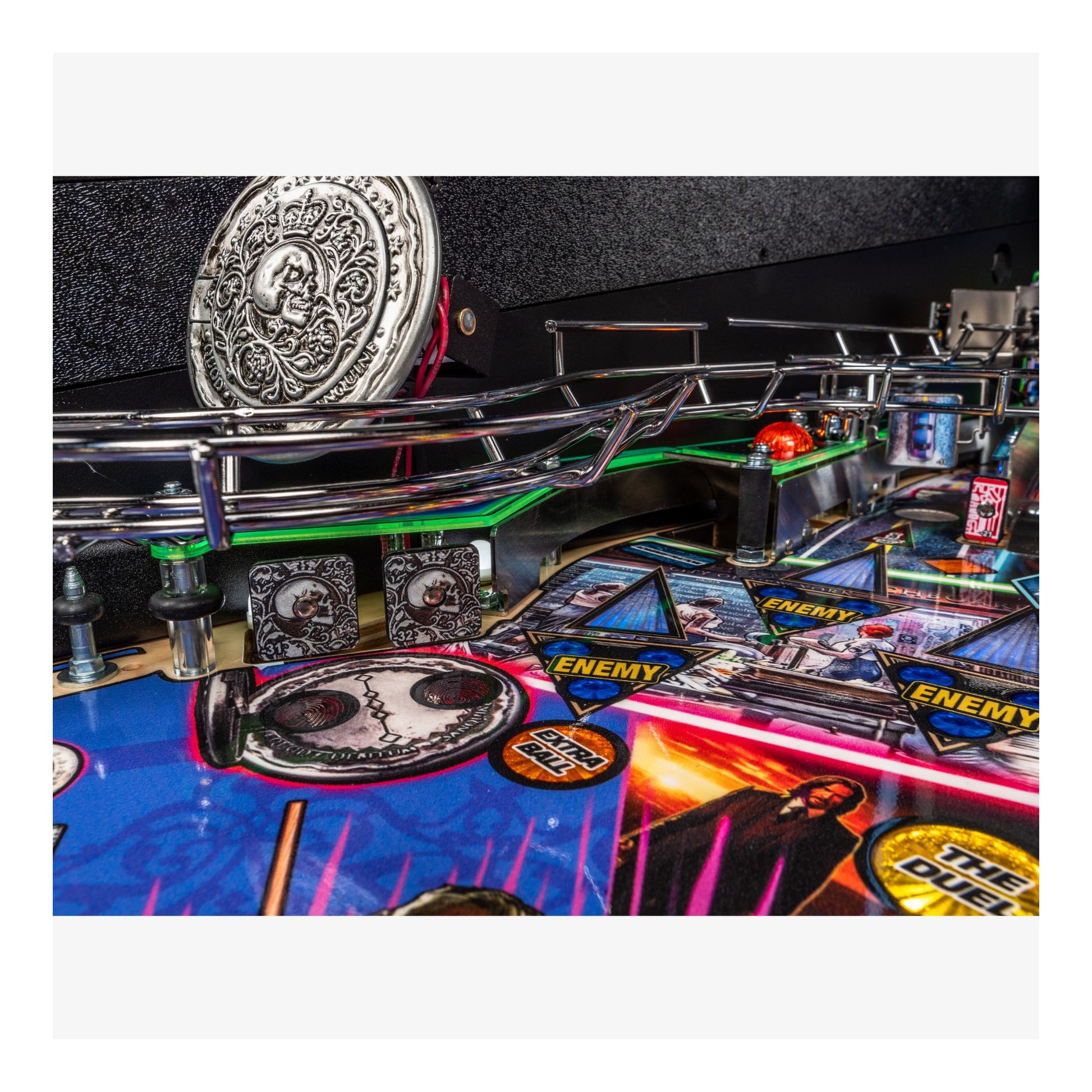 Close-up of a pinball machine with various components and a metallic emblem on top.