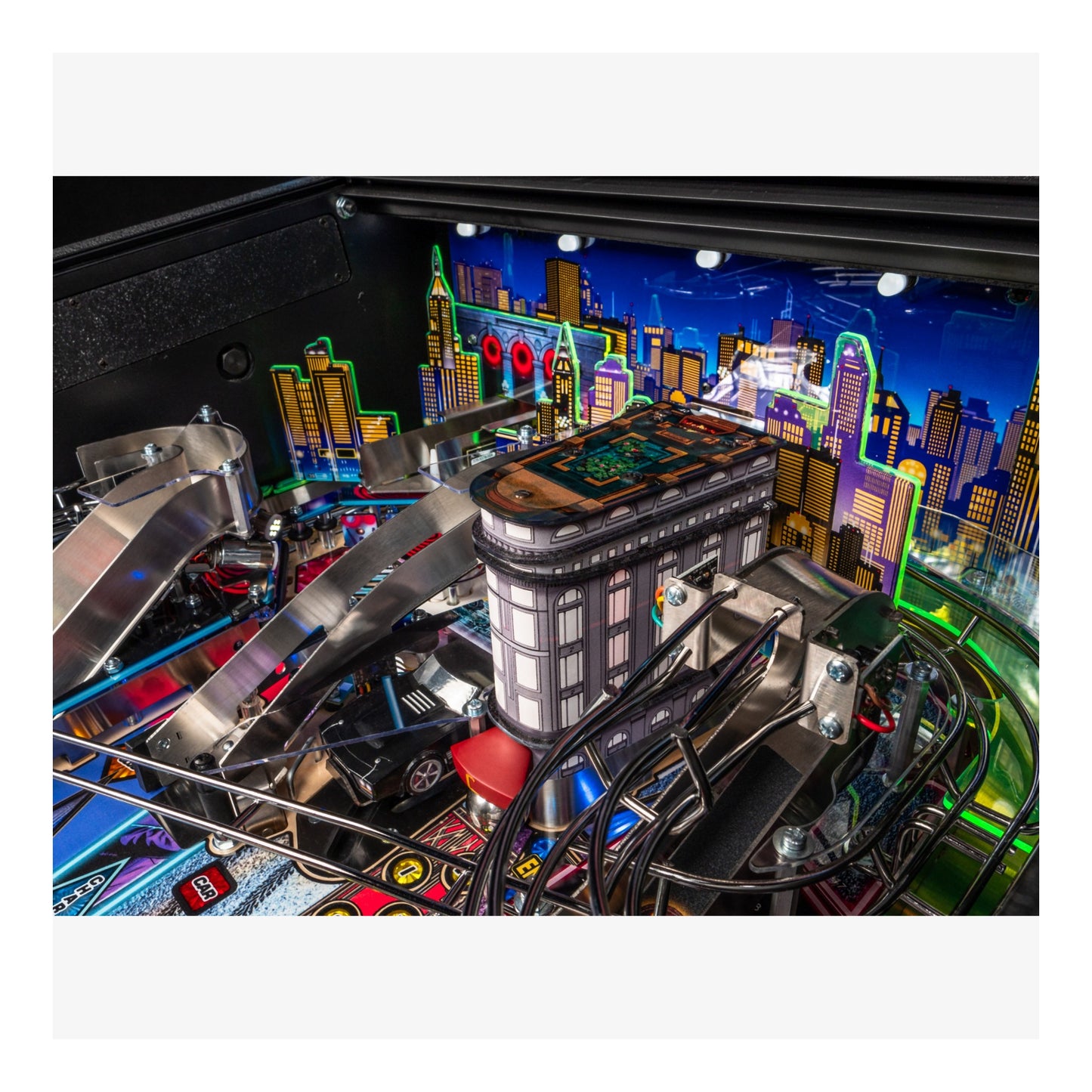 Close-up of a pinball machine with a colorful cityscape background