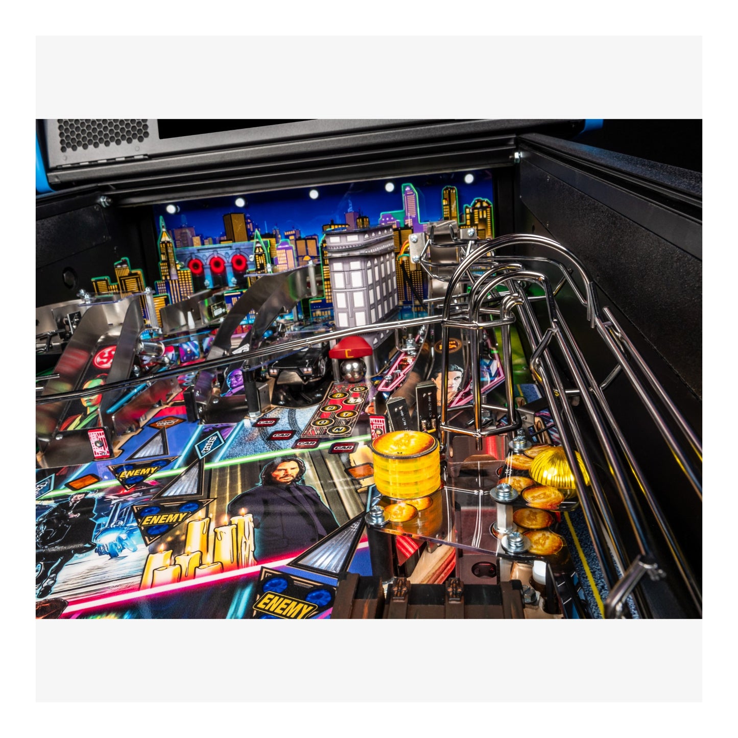 Close-up of a pinball machine with colorful playfield and urban skyline background