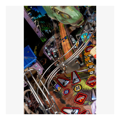 Close-up of a pinball machine with a dinosaur figure and various game components.