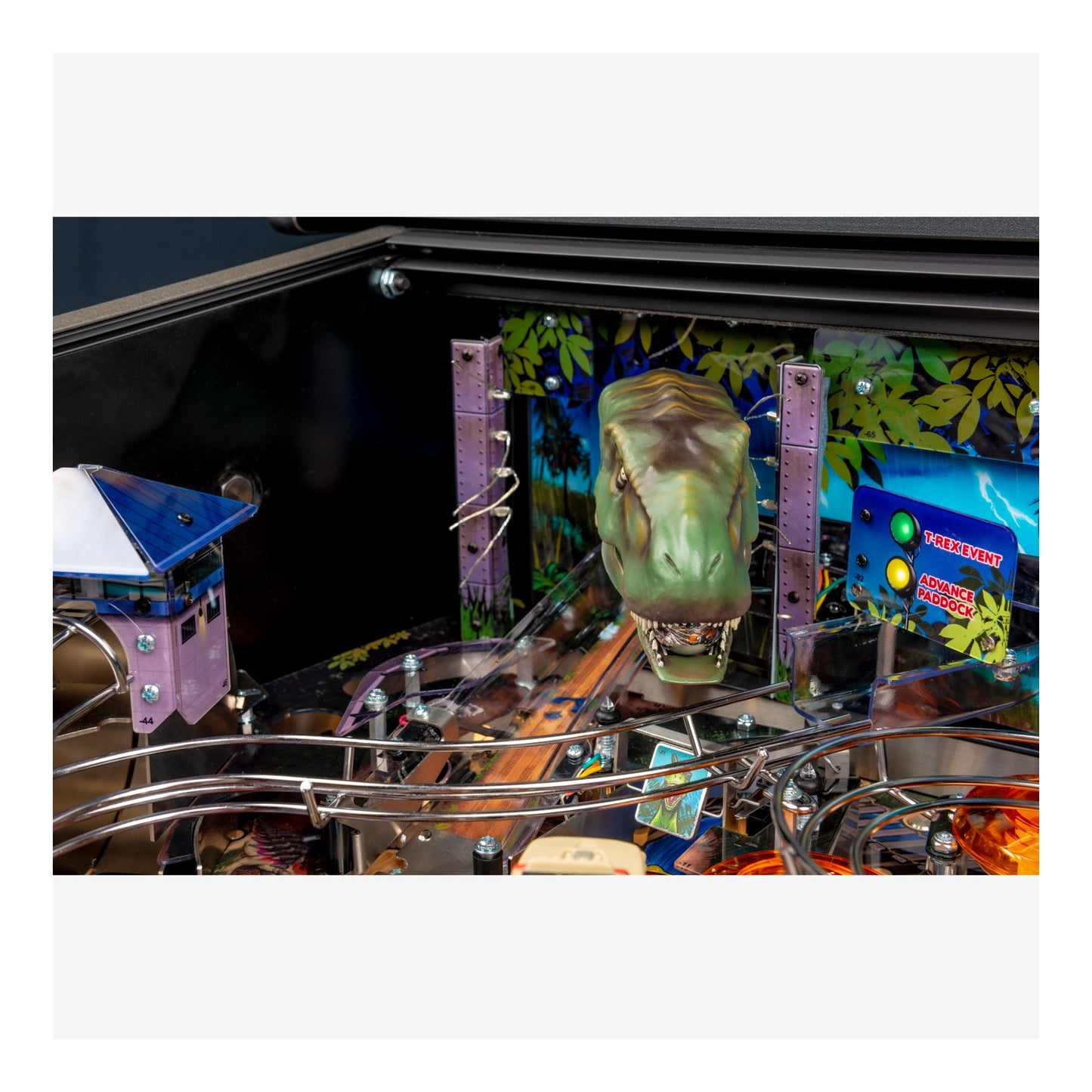 Close-up of a pinball machine with a dinosaur head figure and colorful background