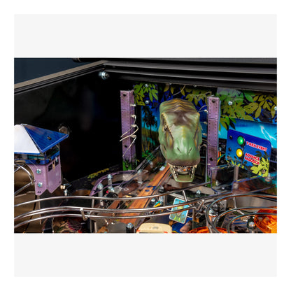 Close-up of a pinball machine with a dinosaur head figure and colorful background