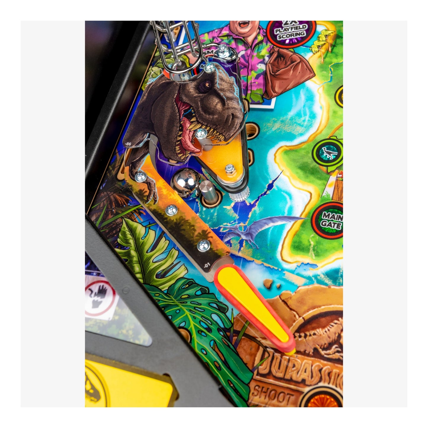 Close-up of a colorful pinball machine with dinosaur and tropical design