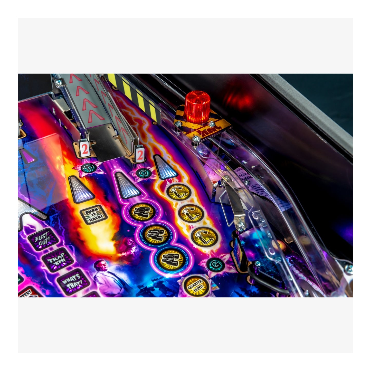 Close-up of a colorful pinball machine with glowing buttons and a red light.