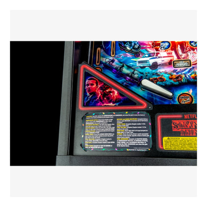 Close-up of a 'Stranger Things' pinball machine with colorful graphics and text.