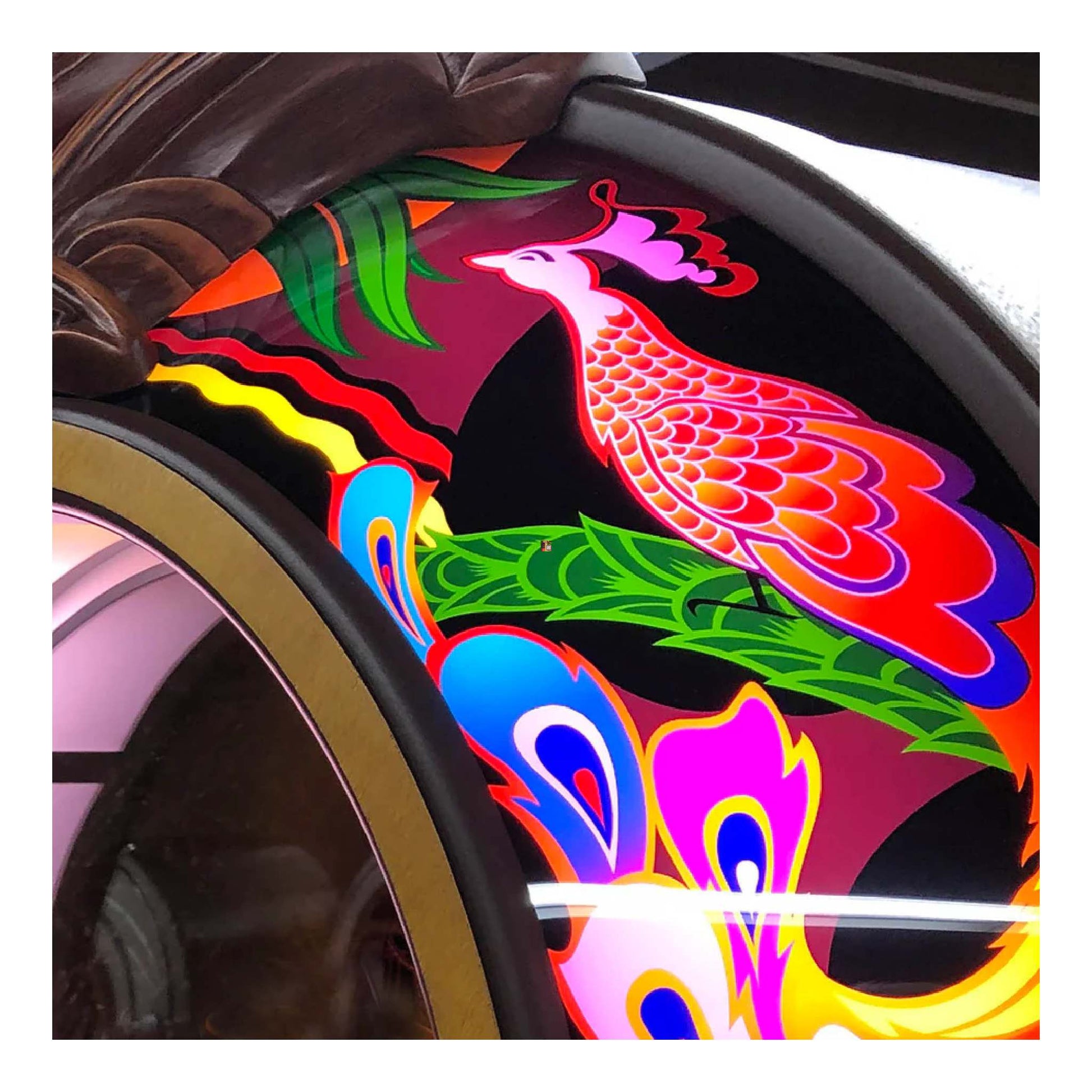 Colorful car rim wrap with a peacock design on a vehicle wheel.