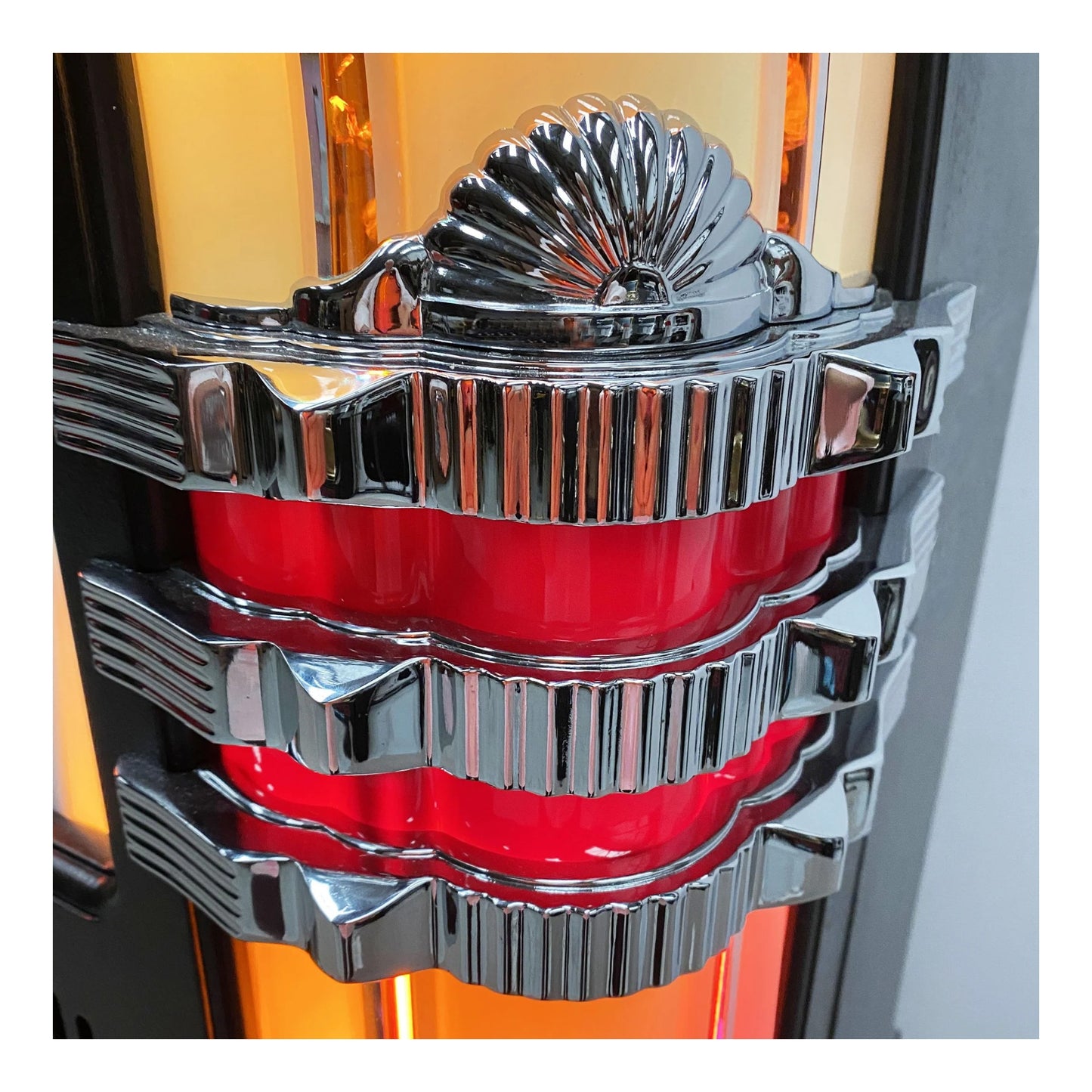 Close-up of a shiny, metallic car emblem with red center on a blurred background