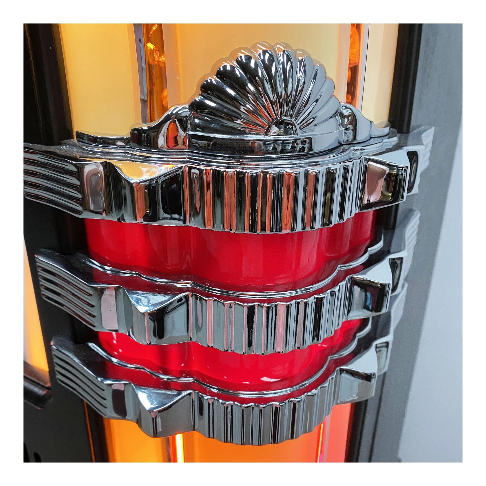 Close-up of a shiny, metallic car emblem with red center on a blurred background