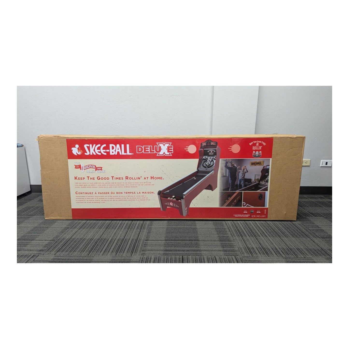 Box of Skee-Ball Deluxe game on a gray floor with white walls.