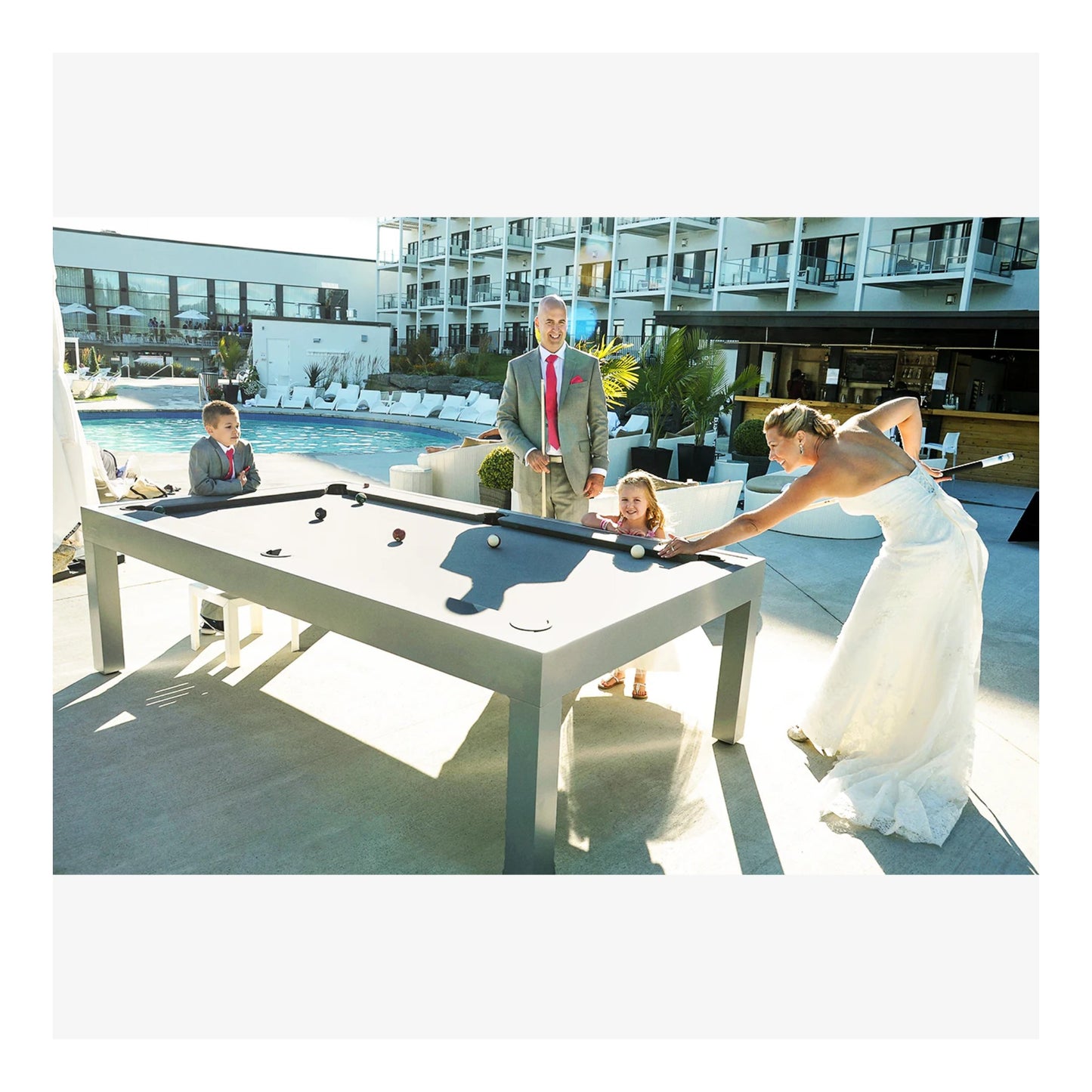 A modern black Storm outdoor pool table with blue Sunbrella cloth on a wooden deck.